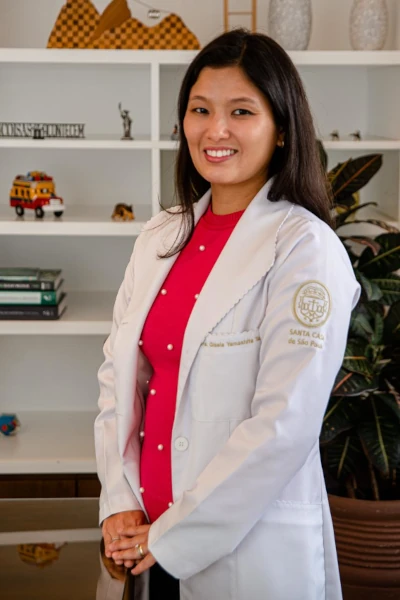 Doutora Gisela Tanno, médica otorrino, sorrindo para foto em seu moderno consultório.